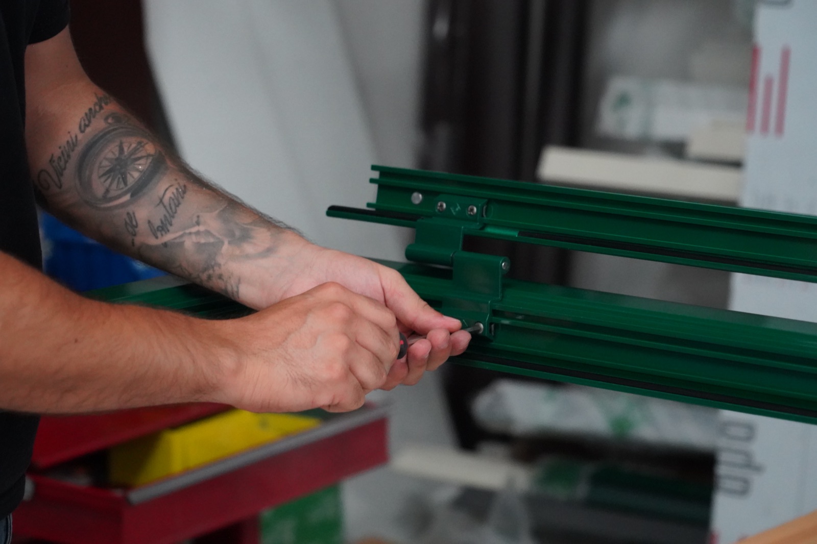 Dettaglio delle mani che avvitano la giunzione di un telaio verde